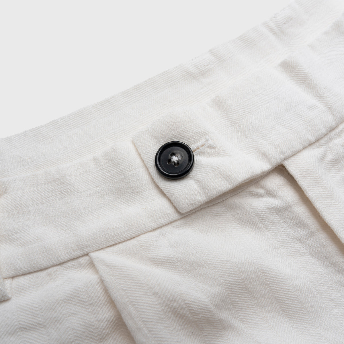 Close-up of a white fabric with a button on a light gray background