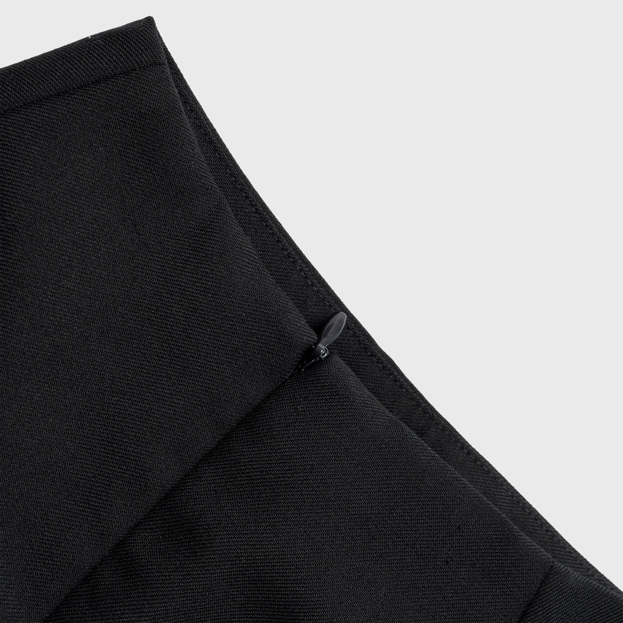 Close-up of a black skirt with a zipper on a light gray background