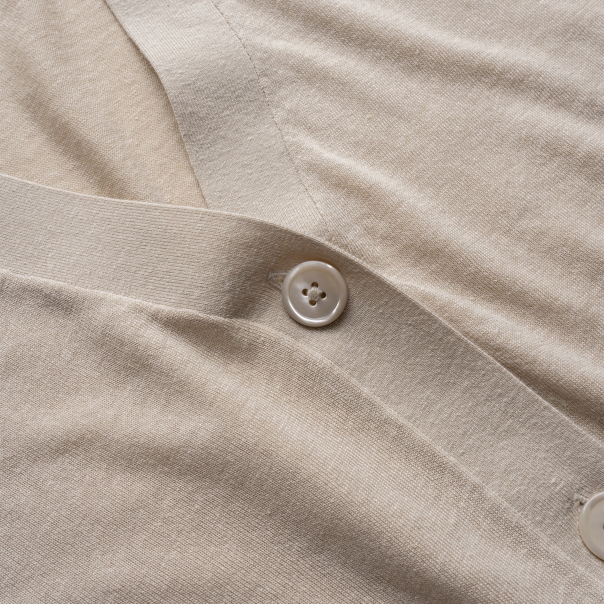 Close-up of beige cardigan with a button