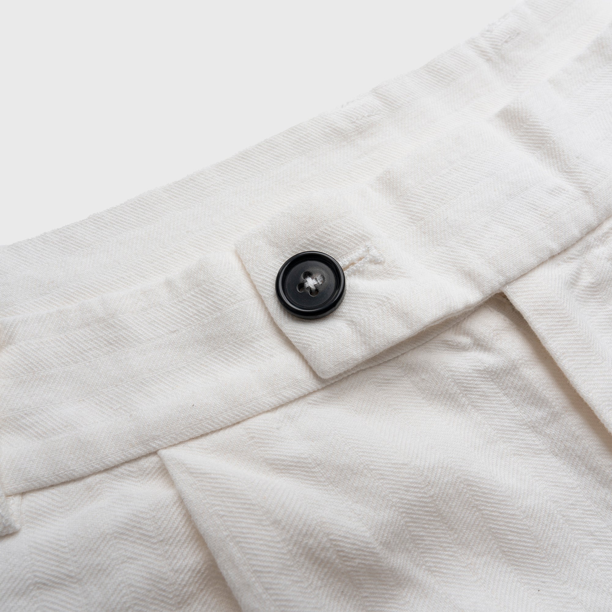 Close-up of a white fabric with a button on a light gray background