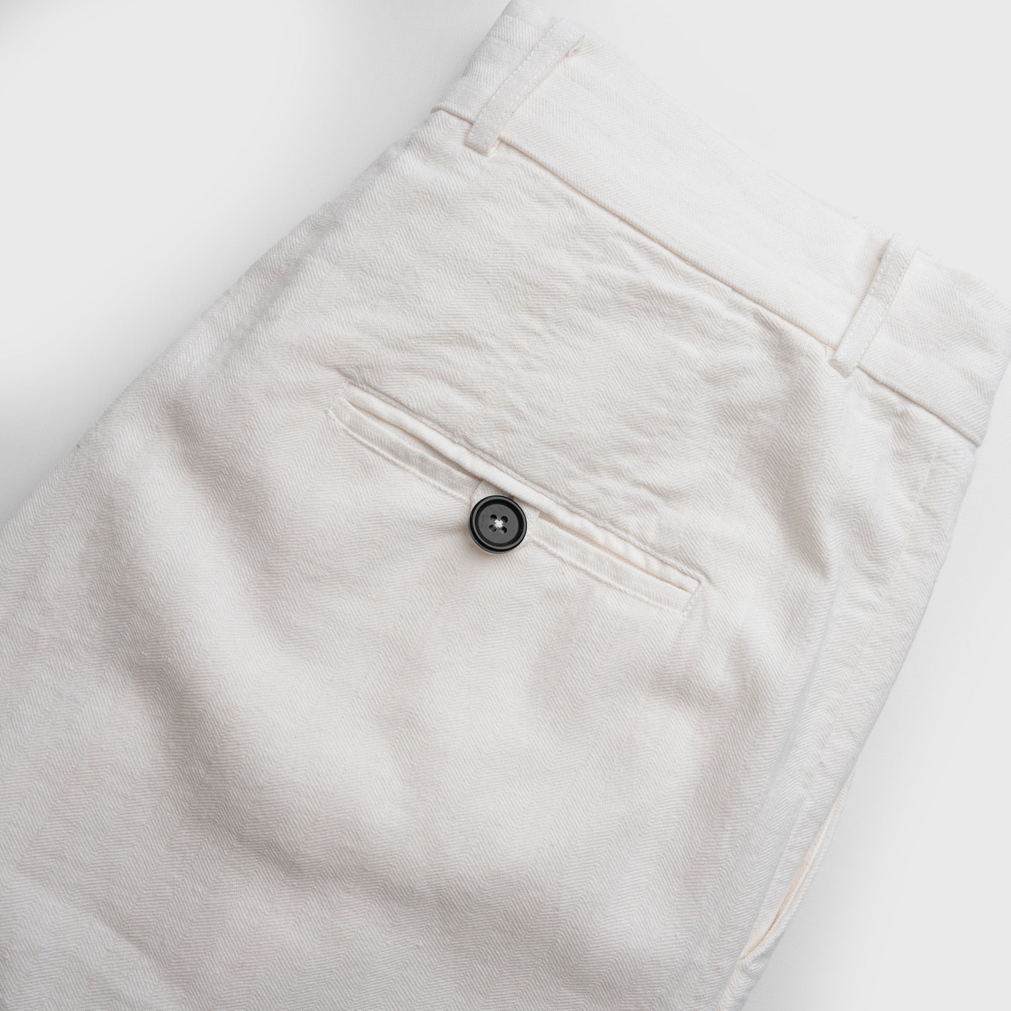 Close-up of white pants with a button on a white background