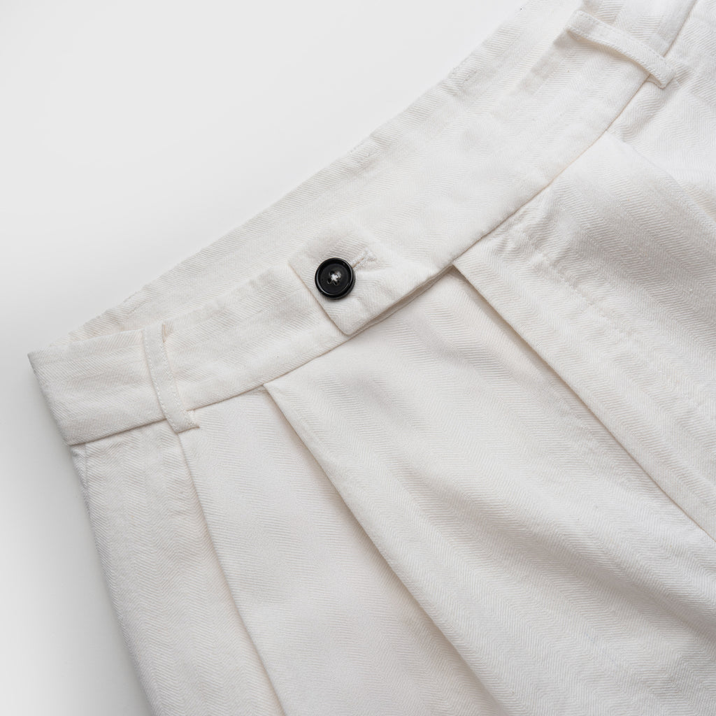 Close-up of white pants with a button on a light gray background