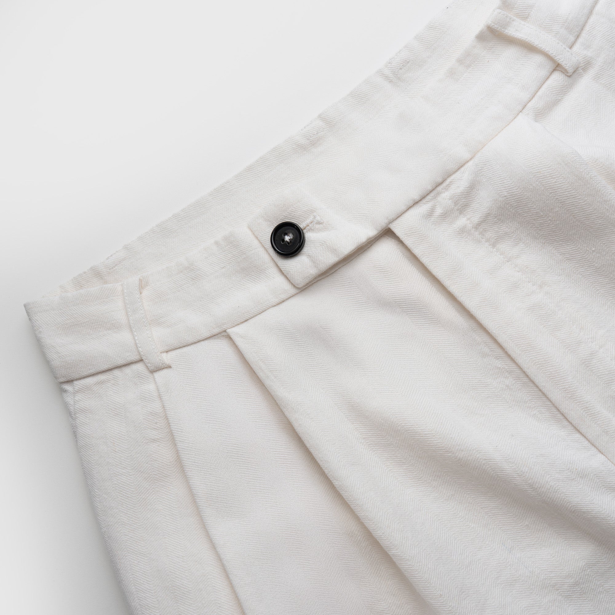 Close-up of white pants with a button on a light gray background