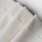 Close-up of folded textured fabric in neutral colors on a light background