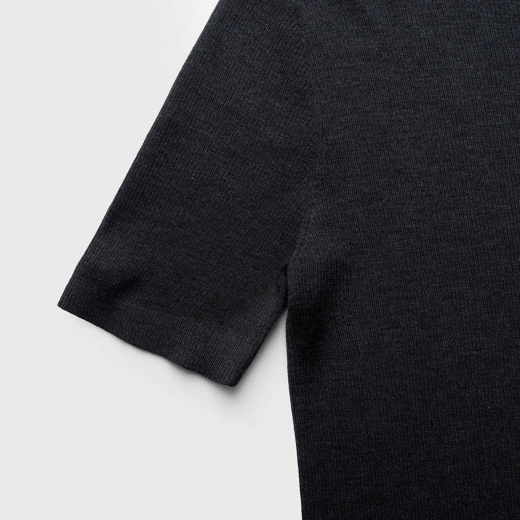 Close-up of a dark gray sweater sleeve on a light gray background