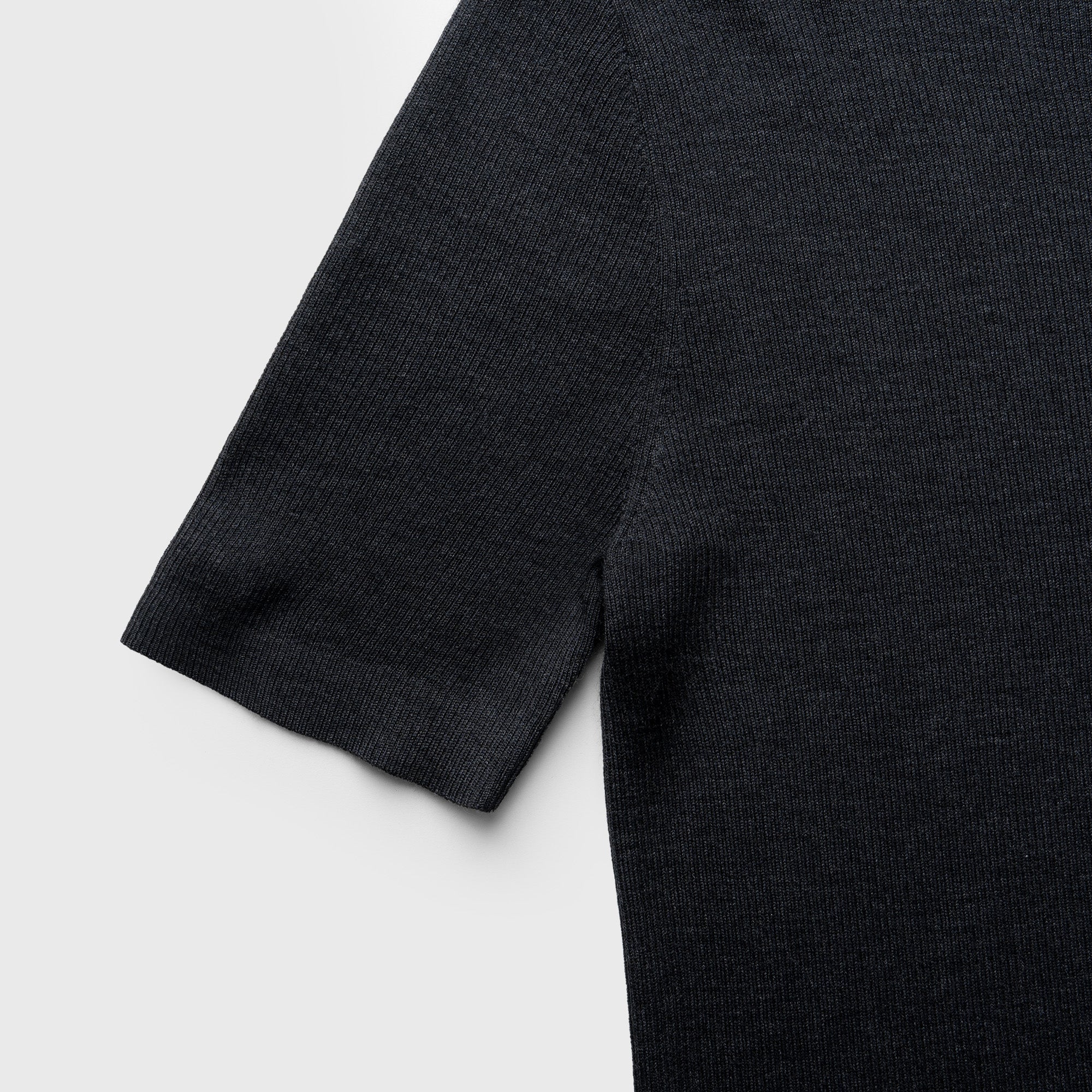 Close-up of a dark gray sweater sleeve on a light gray background