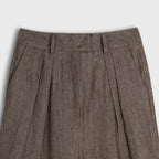 Brown pleated pants on a light gray background