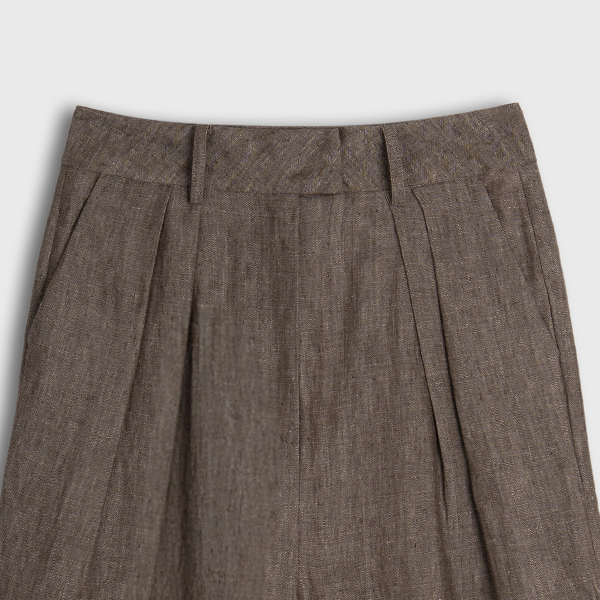 Brown pleated pants on a light gray background