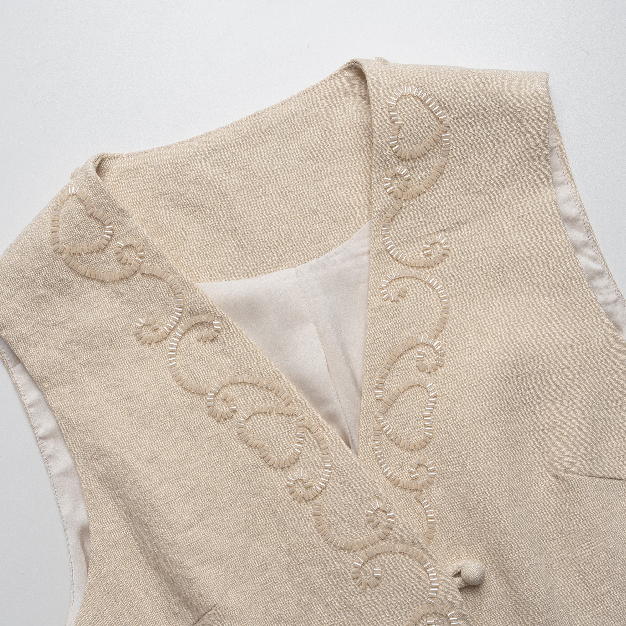 Beige vest with intricate embroidery on a white background