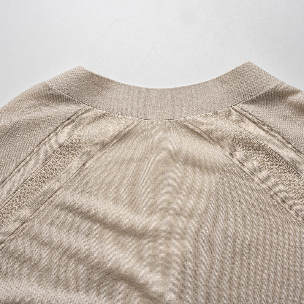 Close-up of a beige cardigan with textured details on a light gray background