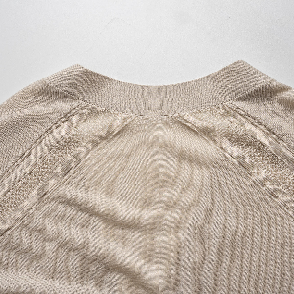 Close-up of a beige cardigan with textured details on a light gray background