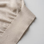 Close-up of beige cardigan with a soft texture on a light gray background