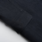 Close-up of a navy fabric with a pocket detail on a light gray background
