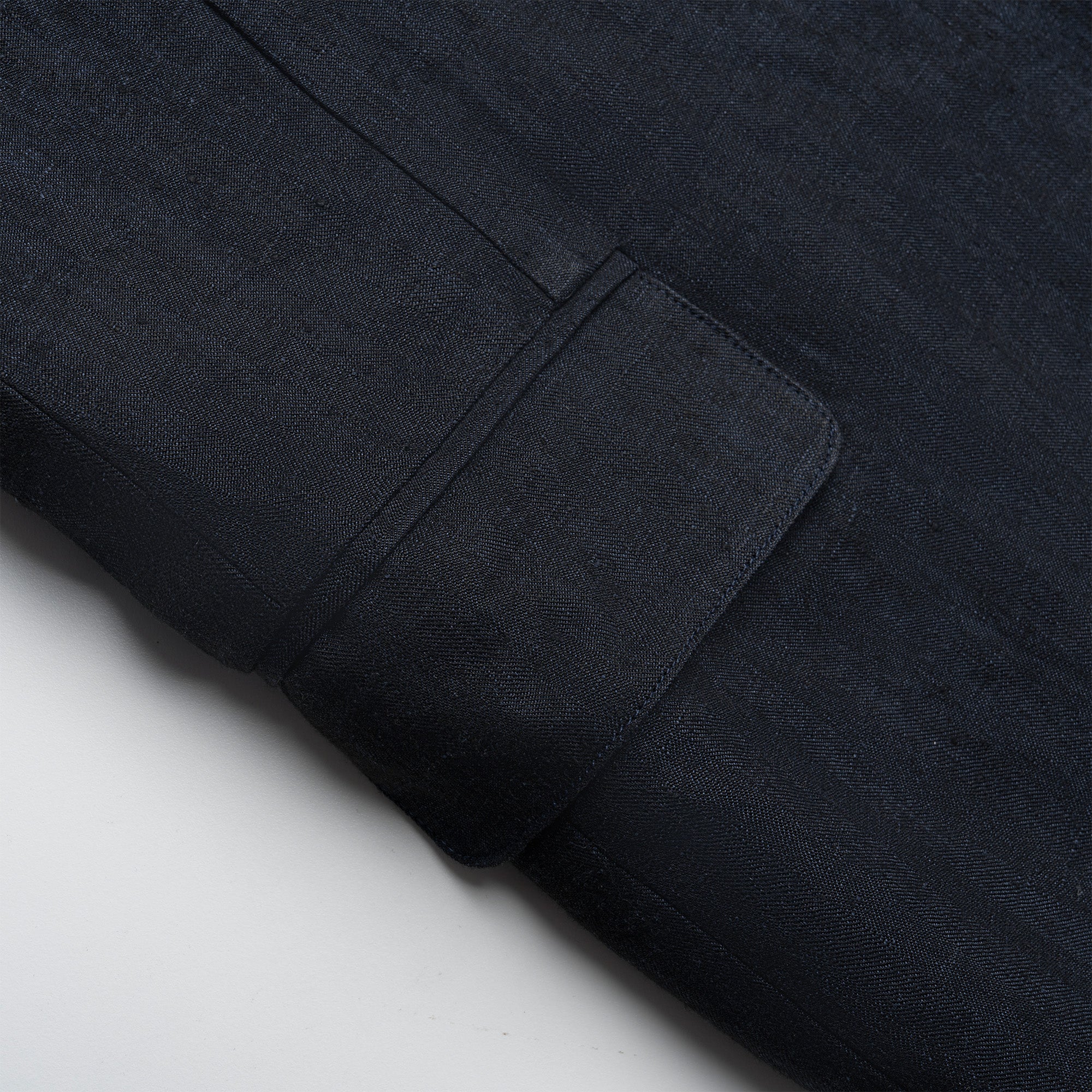 Close-up of a navy fabric with a pocket detail on a light gray background