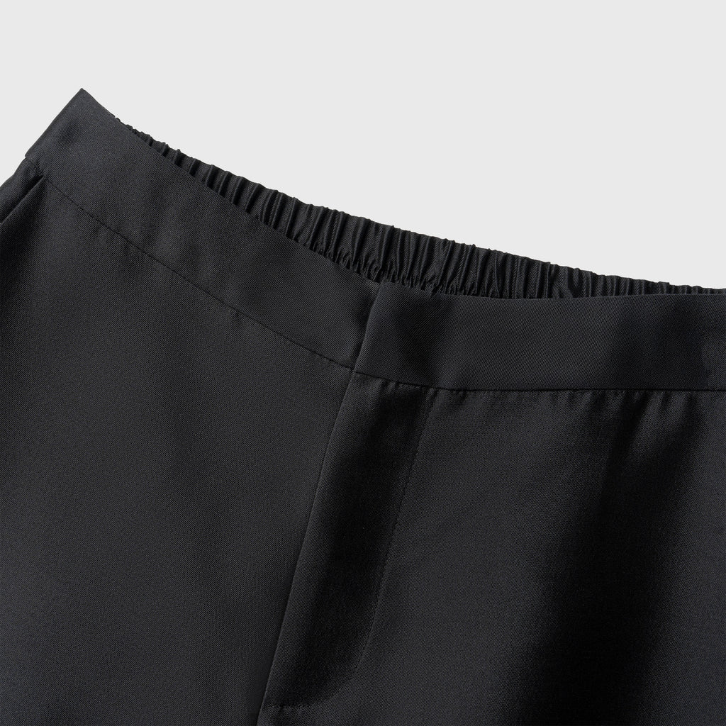 Close-up of black pants with a plain background