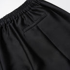 Close-up of black pants with an elastic waistband on a light gray background