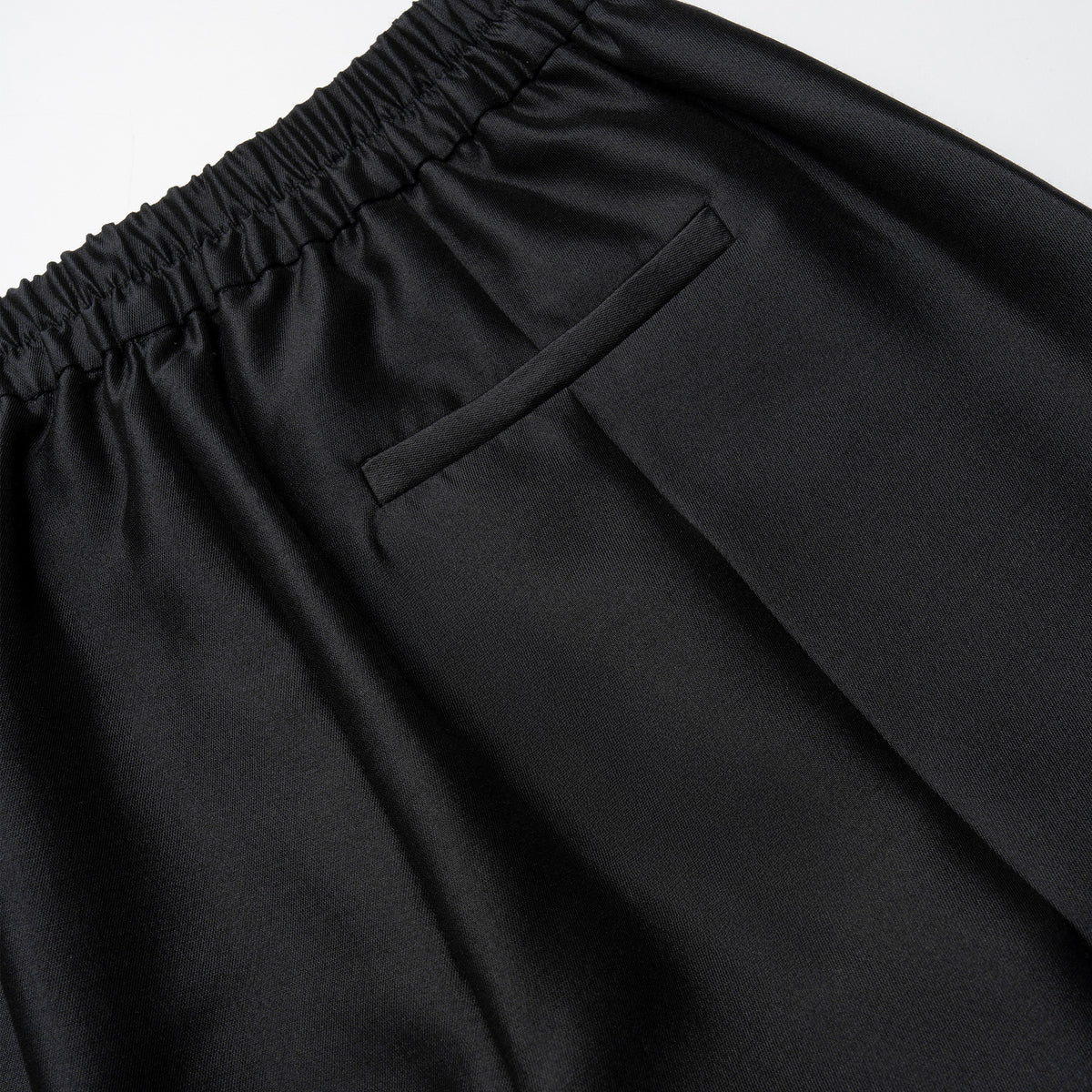 Close-up of black pants with an elastic waistband on a light gray background