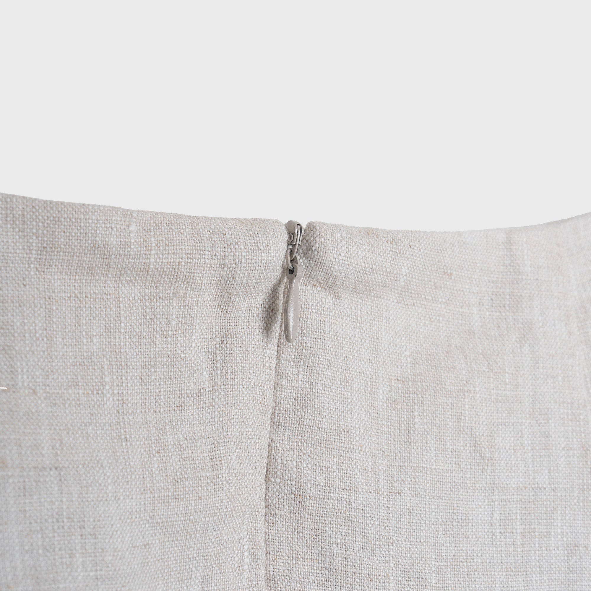 Close-up of a light beige fabric with a zipper on a white background