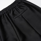 Close-up of black pants with an elastic waistband on a light gray background