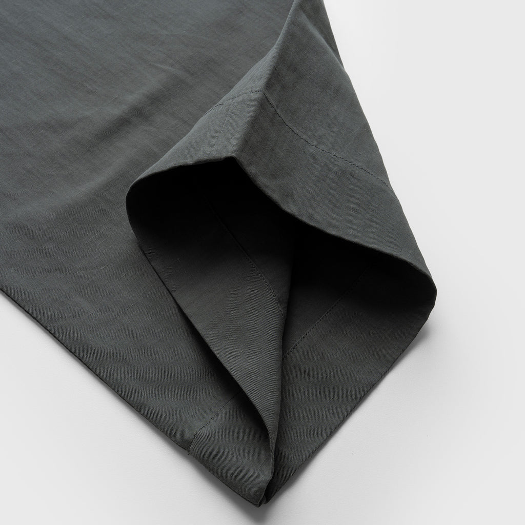 Dark moss green pant fabric with a textured surface on a light gray background