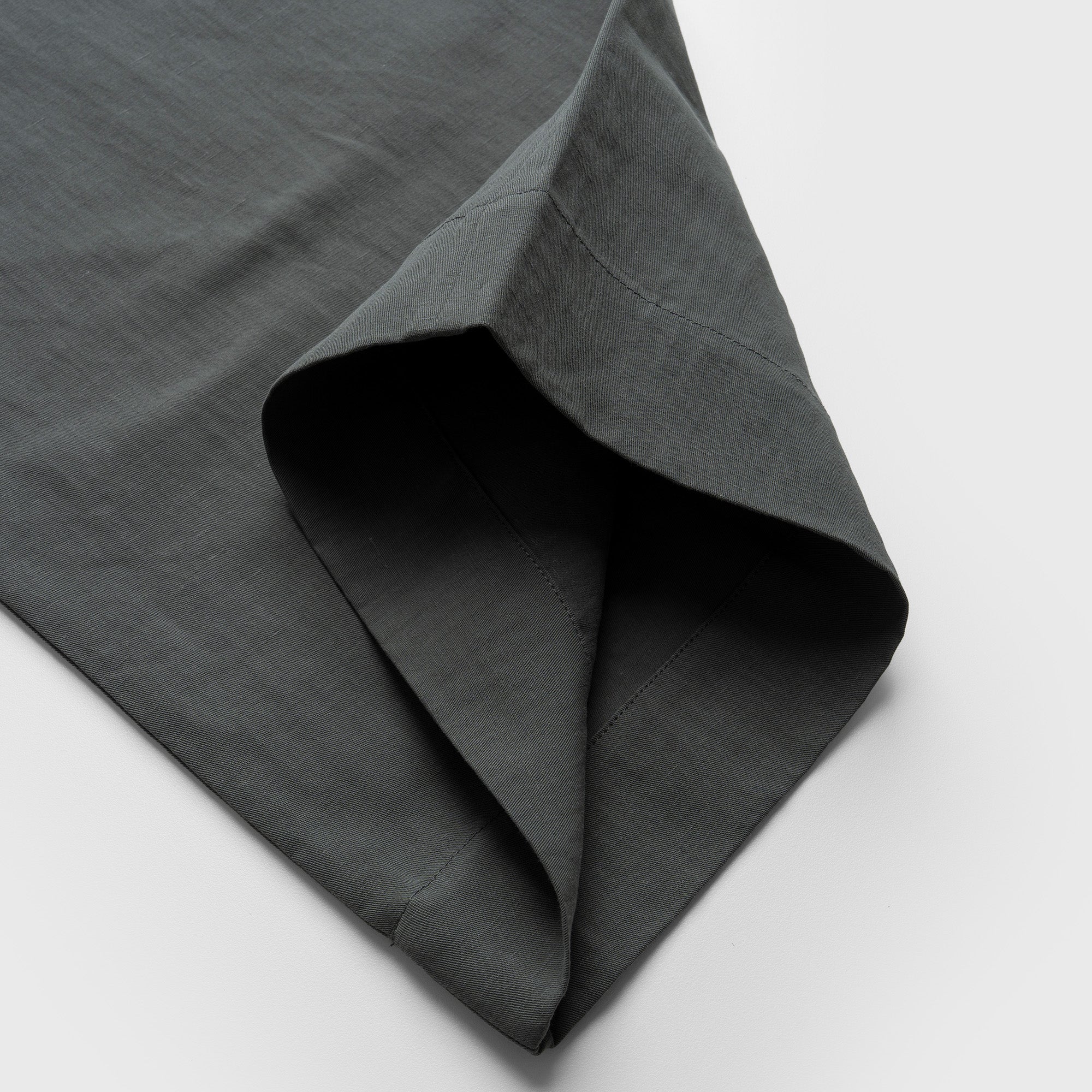 Dark moss green pant fabric with a textured surface on a light gray background