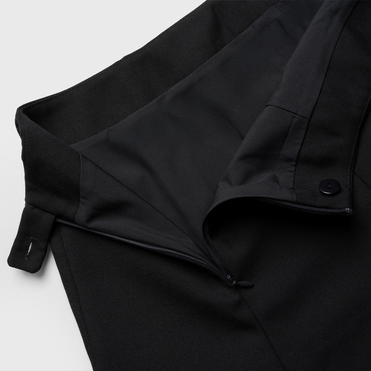 Close-up of a black skirt with a belt on a light gray background