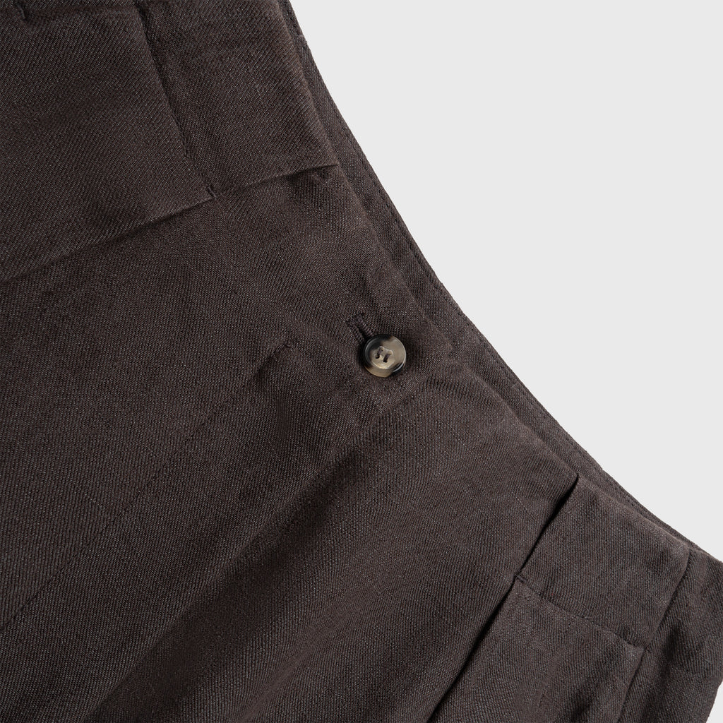 Close-up of dark brown pants with a button on a light gray background