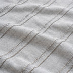 Close-up of textured fabric with wavy lines on a light gray background