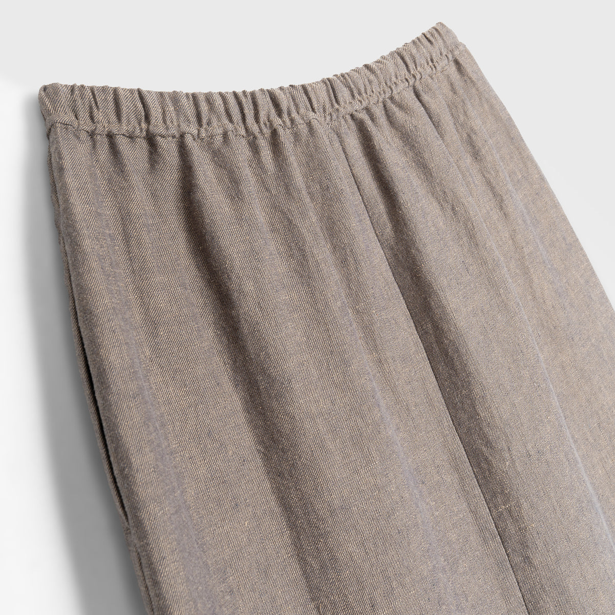 Close-up of beige skirt with an elastic waistband on a light gray background