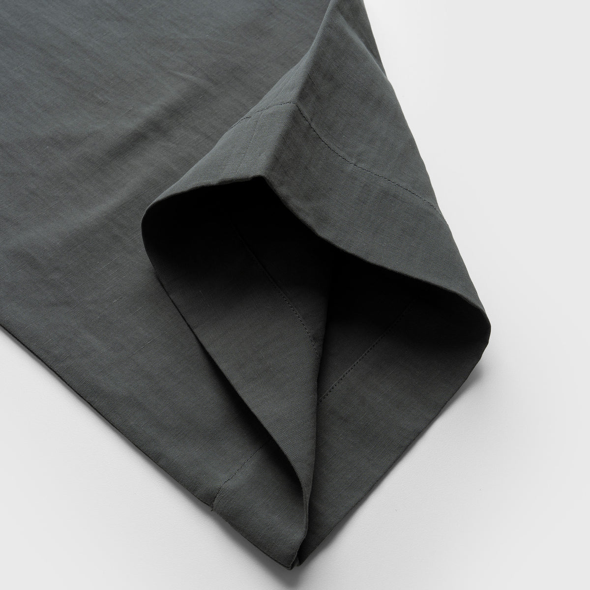 Dark moss green pant fabric with a textured surface on a light gray background
