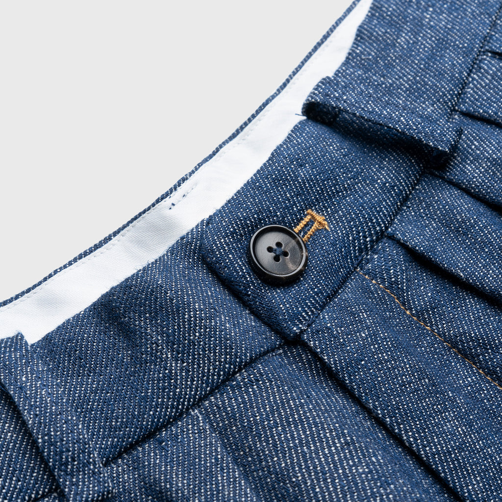 Close-up of a blue hemp denim button on a garment with a white interior lining.