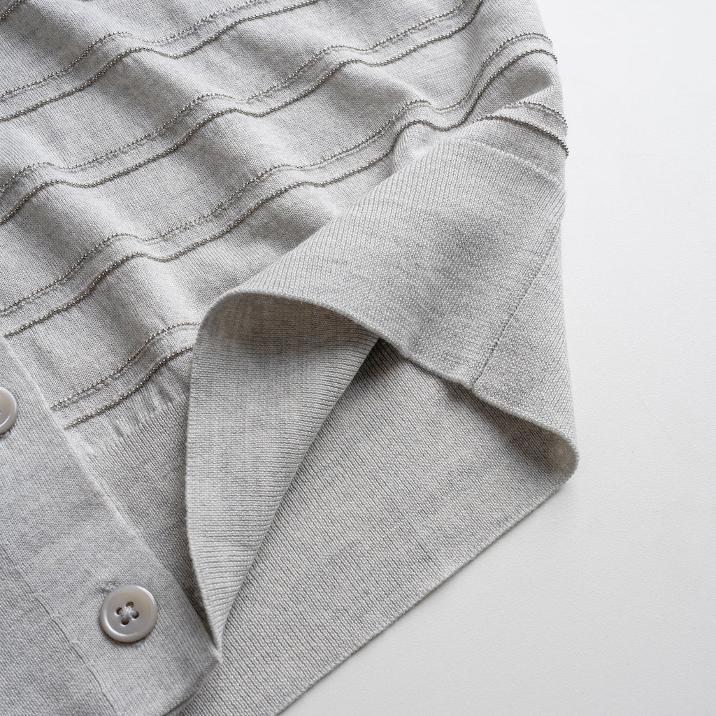 Close-up of a gray textured cardigan with a button on a white background