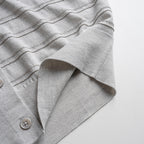 Close-up of a gray textured cardigan with a button on a white background