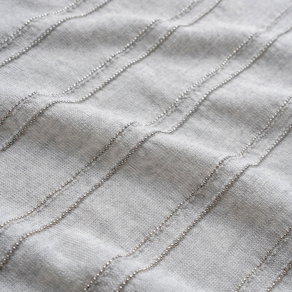 Close-up of textured fabric with wavy lines on a light gray background