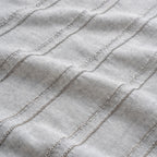 Close-up of textured fabric with wavy lines on a light gray background