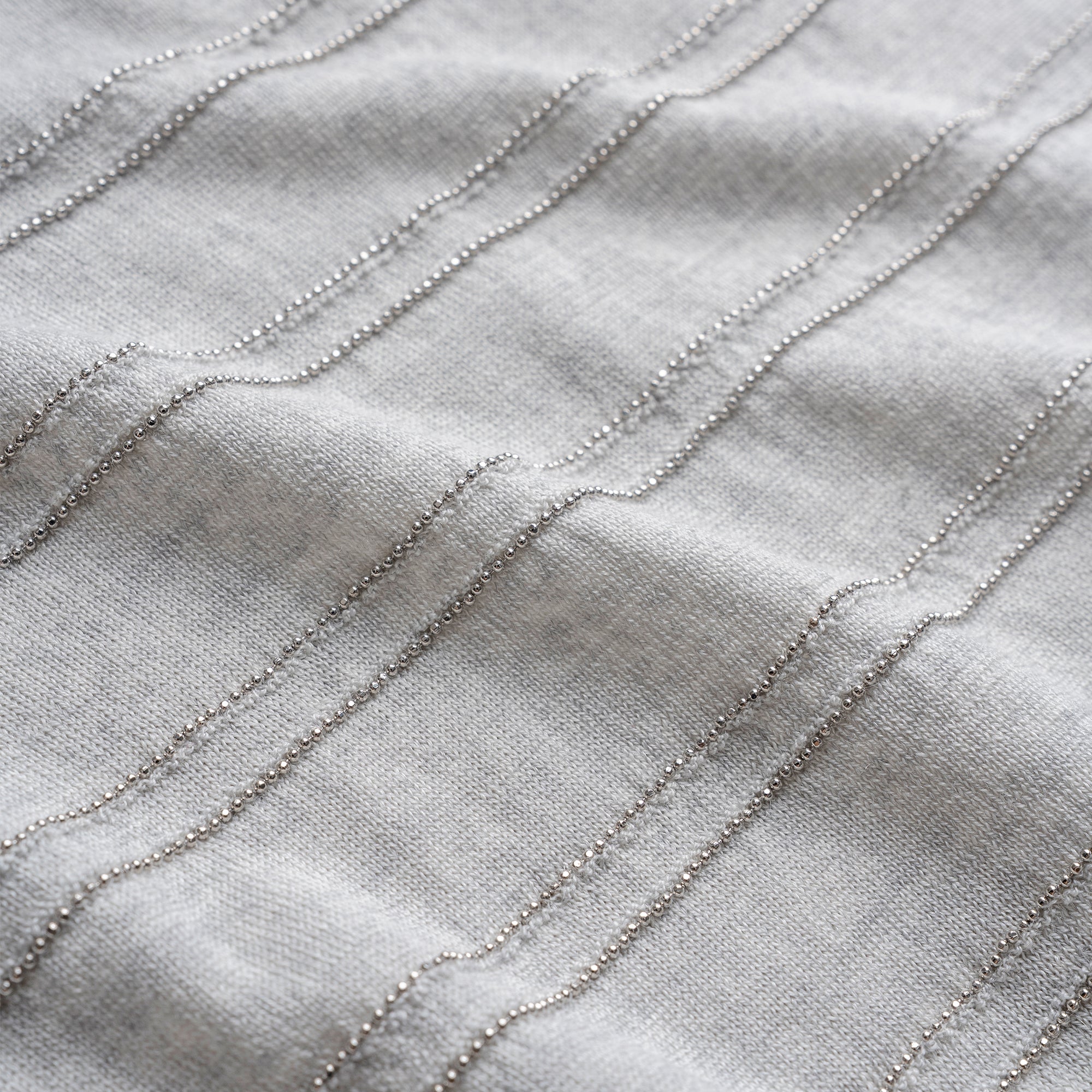 Close-up of textured fabric with wavy lines on a light gray background